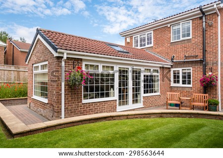 Modern Sunroom external / Modern Sunroom or conservatory extending into the garden, surrounded by a block paved patio