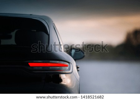 Modern SUV car rear taillamp in the evening. The rear side of a modern crossover in the evening during sunset. The taillight backlight is switched on 