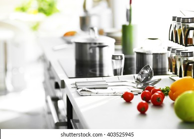 Modern table and electric stove with utensils and vegetables in the kitchen beside window - Shutterstock ID 403525945