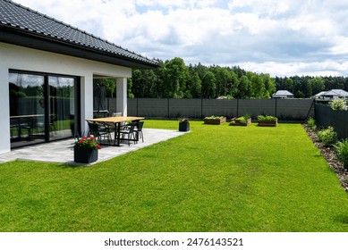 A modern table made of raw wood covered with yacht varnish, standing on the garden terrace.