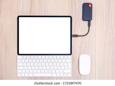 Modern tablet computer, keyboard, mouse and external data storage device on office table. Data storage on ssd.