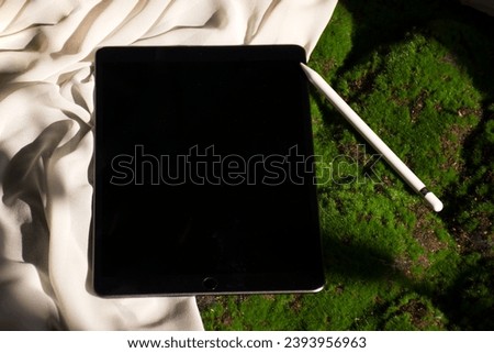 A modern tablet computer resting on a cloth surface beside a decorative object