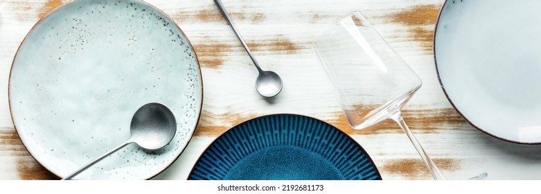 Modern Tableware Panorama With A Vibrant Blue Plate, Cutlery, And A Wine Glass, Overhead Flat Lay Shot. Trendy Dinnerware On A Rustic Background