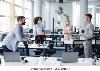 Modern team meeting, group work and social distancing. Manager with tablet speaks with workers in protective masks in interior of modern office with gadgets during coronavirus epidemic, free space - Shutterstock ID 1827501677