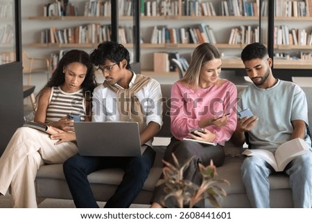 Modern tech in peer learning. Multiracial group high school students zoomers engaged in productive collaborative studying in library share information online using gadgets talk discuss exchange ideas
