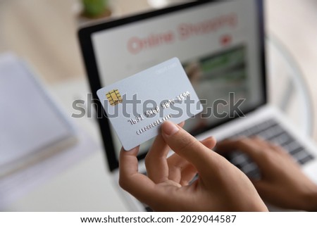 Modern tech usage, easy comfort e-shopping from home, secure electronic payment, cashback concept. Close up above view female hands holds credit card use laptop makes e-pay through e-bank application