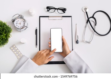 Modern Technologies In Healthcare Sector. Male Doctor Using Smartphone With Blank Screen At Workplace, Top View