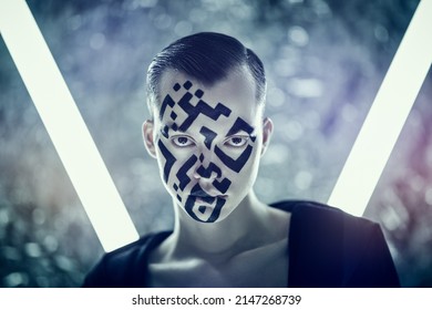 Modern technologies of human personification. Portrait of a young man with a QR-code painted on his face, who stands in front of futuristic neon lamps and looks at the camera aggressively. 