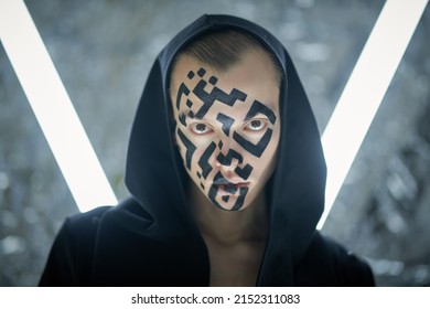 Modern technologies of human personification. Portrait of a young man with a QR-code painted on his face standing in front of futuristic neon lamps and looking unfriendly at the camera. 