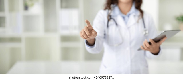 Modern technologies in medicare, healthcare and gadgets. Cropped of woman in white medical coat doctor with digital tablet in her hand touching invisible screen, panorama with copy space - Powered by Shutterstock