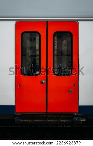 Modern technologies for opening sliding doors of an electric train car using a touch button. Closed red doors of a passenger car as part of a subway train. A vehicle for fast travel.