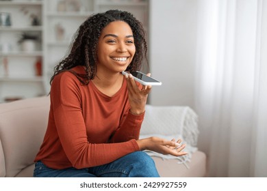 Modern Technologies. Portrait Of Happy Young Black Woman Recording Voice Message On Smartphone While Relaxing At Home, Smiling African American Woman Browsing Virtual Assistant On Mobile Phone - Powered by Shutterstock