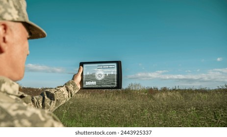 Modern technology in the army. Warfare analytic operator checking coordination of the military team. Military commander with a digital tablet device with augmented reality operating troops outdoors. - Powered by Shutterstock