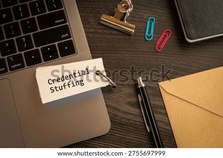 Modern technology concept of Credential Stuffing on word card with laptop, clips, pen. Digital innovation and connectivity visualization.