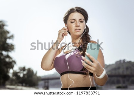 Similar – Woman with earphones listening music in smartphone