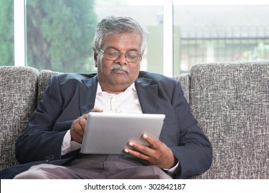 Modern Technology. Old Indian Man Using Touch Screen Tablet Computer At Home. Asian Senior People Living Lifestyle Indoors.