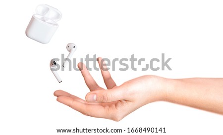 Modern technology white pods headphones flying, soar on hand isolated on white background. Wireless earphones device. New way to leasten music. Concept of new technology hardware. Copy space