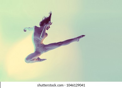 Modern teen contemporary dancer poses in front of the studio background. Toned image. Like a doll view. dance in flight