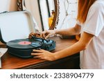 A modern teenage girl with dyed hair turns on a retro record player, meeting modern with retro