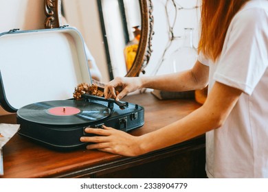 A modern teenage girl with dyed hair turns on a retro record player, meeting modern with retro