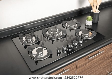 A modern tempered glass gas stove with five gas burners inside a contemporary melamine wood kitchen
