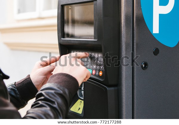 A modern terminal for paying for car parking. The\
person presses the buttons and pays for the parking. Modern\
technology in everyday life.
