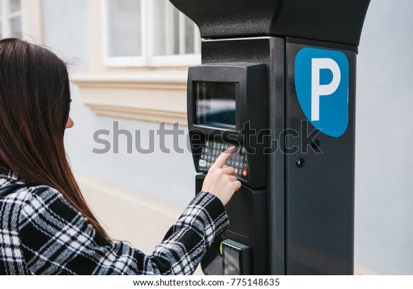A modern terminal for paying for car\
parking. A young woman presses a button and tries to pay for a car\
parking. Modern technology in everyday\
life.