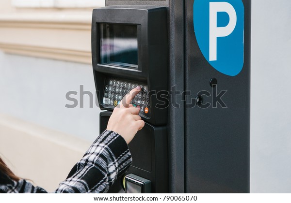 A modern terminal for paying for car parking. The
person presses the buttons and pays for the parking. Modern
technology in everyday life.