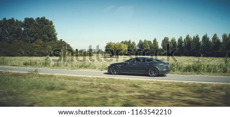 Modern Tesla driving on a free green road. Electric car lifestyle modern look. editorial 