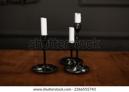 Similar – Image, Stock Photo Modern three black glass candlesticks with white candles on wooden table in antique style on dark wall background. Minimalist elegant decor with candle holders with wax different size.