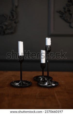Similar – Image, Stock Photo Modern three black glass candlesticks with white candles on wooden table in antique style on dark wall background. Minimalist elegant decor with candle holders with wax different size.