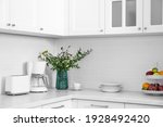 Modern toaster, coffeemaker and dishware on countertop in kitchen