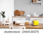 Modern toaster with jar of jam and toasts on table in kitchen
