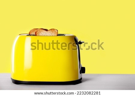 Modern toaster with slices of roasted bread on white wooden table. Space for text