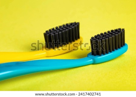 Modern toothbrushes with carbon coating on a yellow background, close-up. Toothbrushes with medium-hard bristles. Oral care and hygiene.