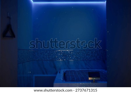 A modern, touchless, dark room floatation bath.A closed-surface spa capsule with touchscreen controls in a room with soft lighting