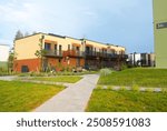 Modern townhouses in a residential area. New apartment buildings with green outdoor facilities in sustainable enviroment. Street  with Two-story townhouses. Townhouse along sidewalk with green lawn.