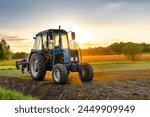 Modern tractor machinery plowing agricultural field meadow at farm at spring autumn during sunset.Farmer cultivating,make soil tillage before seeding plants,crops,nature countryside rural scene.