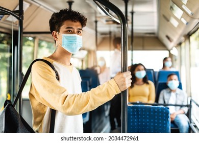 Modern Travel Transportation. Portrait of asian male passenger in disposable medical mask holding on handrails in urban bus. Concept of city trip in context of covid pandemic, cororna virus quarantine