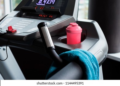 modern treadmill with blue towel and pink shaker standing on it. concept of sports equipment