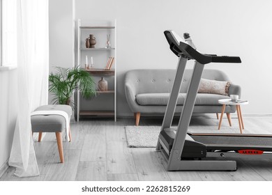 Modern treadmill in interior of light room