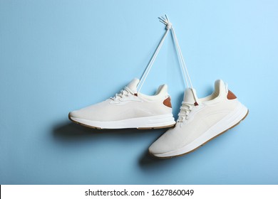 Modern trendy sneakers hang on laces on a colored background. Casual shoes, sports shoes. Place to insert text. - Powered by Shutterstock