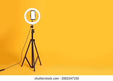 Modern tripod with ring light and smartphone on yellow background. Space for text - Shutterstock ID 2002547150