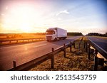 A modern truck with a refrigerator semi-trailer with refrigeration equipment transports flower products while maintaining the temperature regime against the backdrop of sunset and forest. 