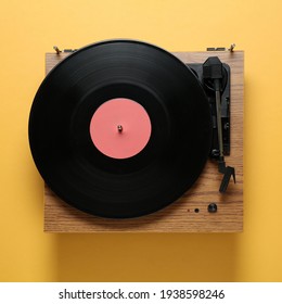 Modern turntable with vinyl record on orange background, top view
