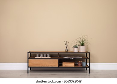 Modern TV cabinet with decor near beige wall. Space for design