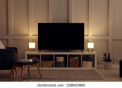 Modern TV on cabinet, armchair and lamps indoors. Interior design - Shutterstock ID 2188423885