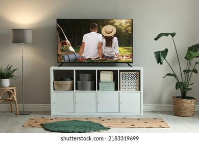 Modern TV Set On Wooden Stand In Room. Scene Of Romantic Movie On Screen