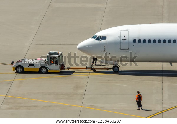 Modern twin engine civil airplane pushing back at\
international airport