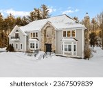 A modern two-story house on snowy winter landscapewith trees in New England